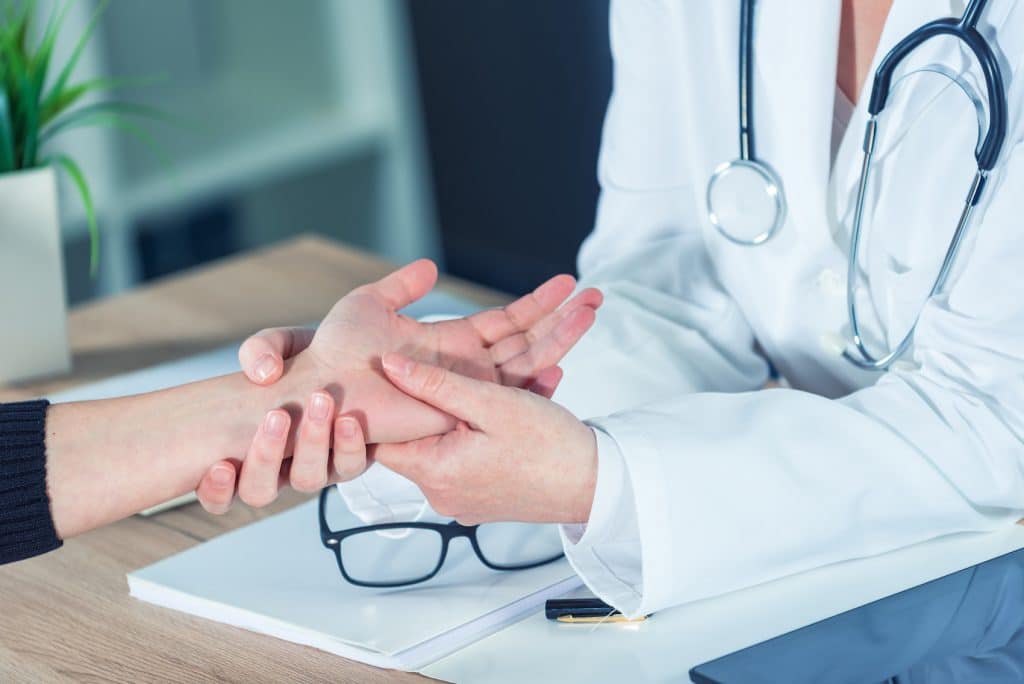 doctor examining a patient's writs for joint injection