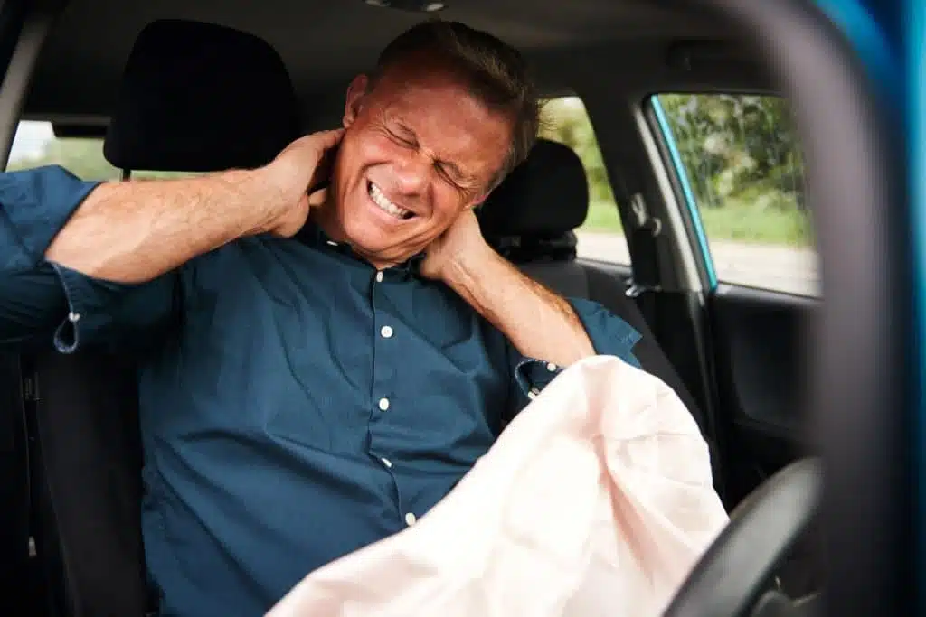 business man holding his neck while inside his car scaled image