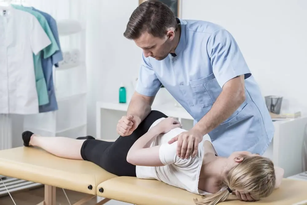 Chiropractor giving lower back adjustment to female patient.