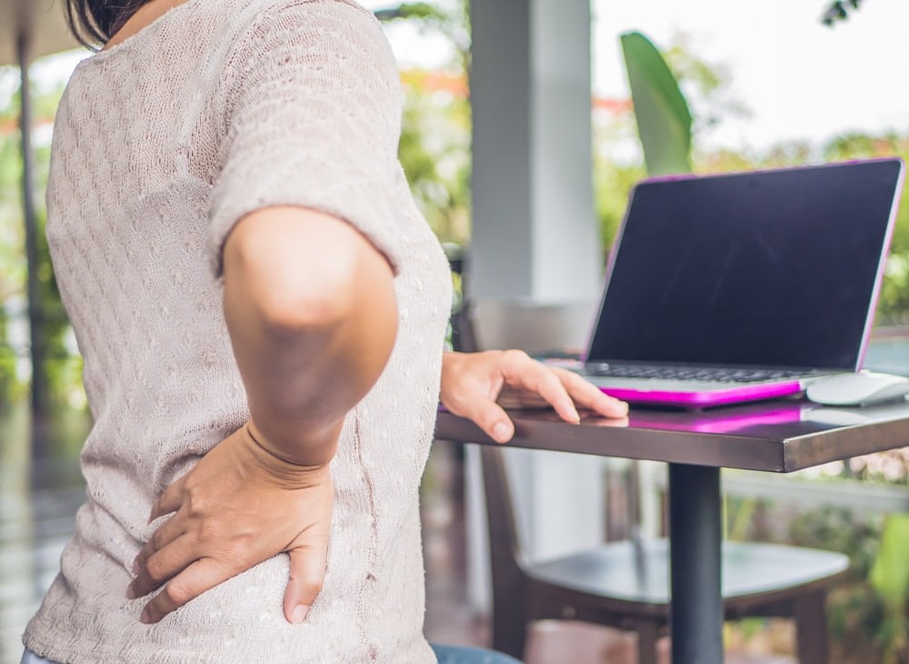 woman on her laptop having back pain