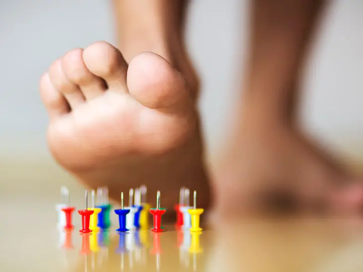 thumbtacks facing upward while a foot is about to step on them