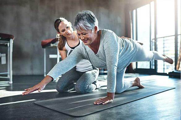 Physical therapist helping a senior patient do therapeutic exercises.