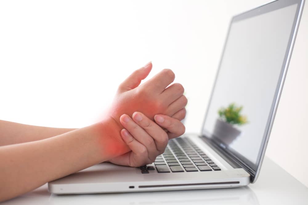 hands in pain on a laptop - hand pain treatment