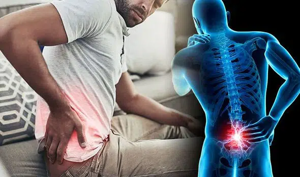 Man sits on couch with back pain from a work injury