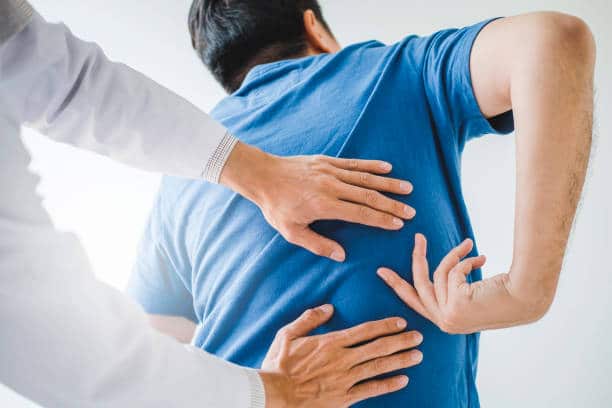 chiropractor examining a patient's back for sciatica pain