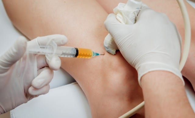 Doctor doing the platelet-rich plasma injection to the knee of the patient