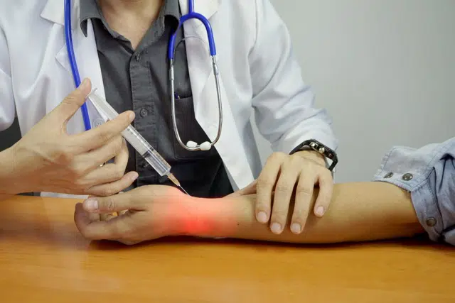 doctor giving  patient joint injection on his wrist