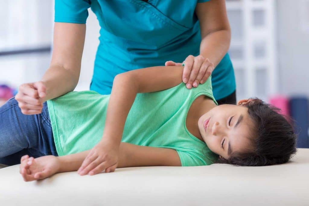 Young patient having pediatric chiropractic treatment in rehabilitation center