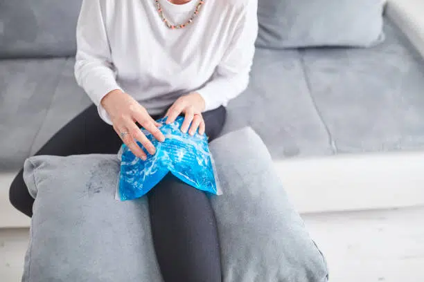 Injured woman holding ice pack for cooling down the knee inflammation