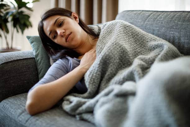 Woman suffering from fatigue feeling so tired and weak laying on the couch