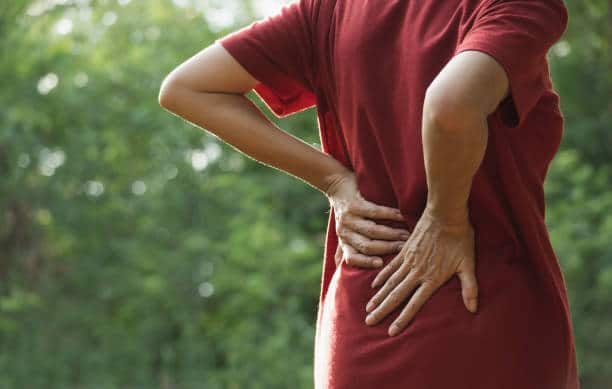 woman suffering from back pain during outdoor exercise