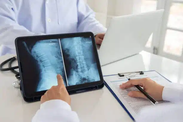 lumbar vertebrae x-ray image by MRI  on digital tablet screen with medical team for consult.