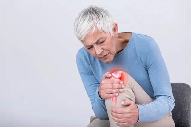 Senior woman holding the knee with pain suffers from knee osteoarthritis
