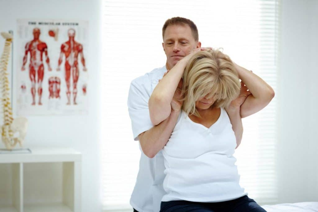 Male doctor chiropractor doing some chiropractic adjustment to the woman patient's back.