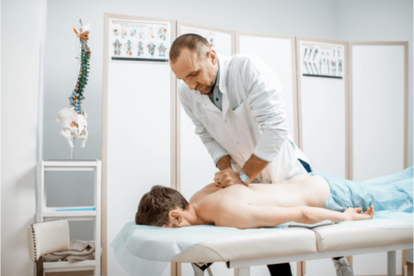 Male doctor chiropractor doing some chiropractic adjustment to the senior patient.