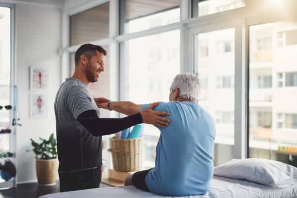 Physiotherapist helping a senior patient with his physical therapy treatment.