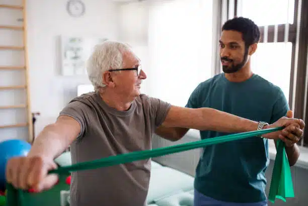 Physiotherapist helping a senior patient with his physical therapy treatment.