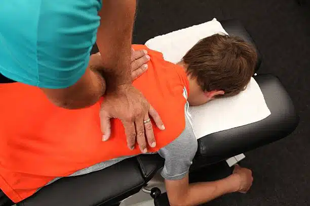 Chiropractor doing some chiropractic adjustment to a young patient.