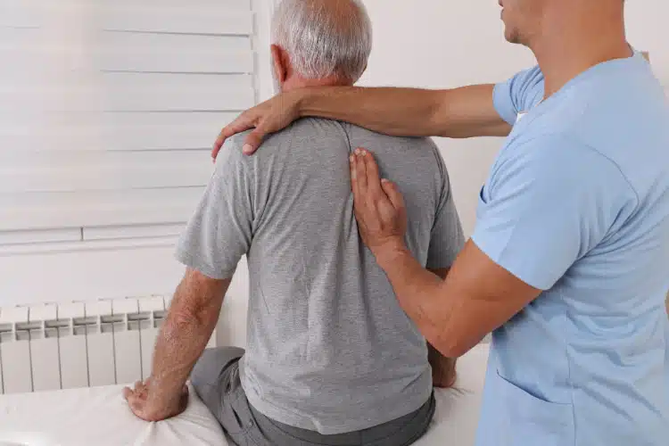senior man under going a pain management treatment at a chiropractic clinic.