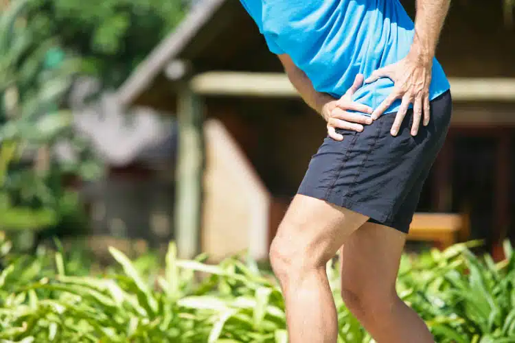 Man suffers from severe hip pain while doing some outdoor exercise.
