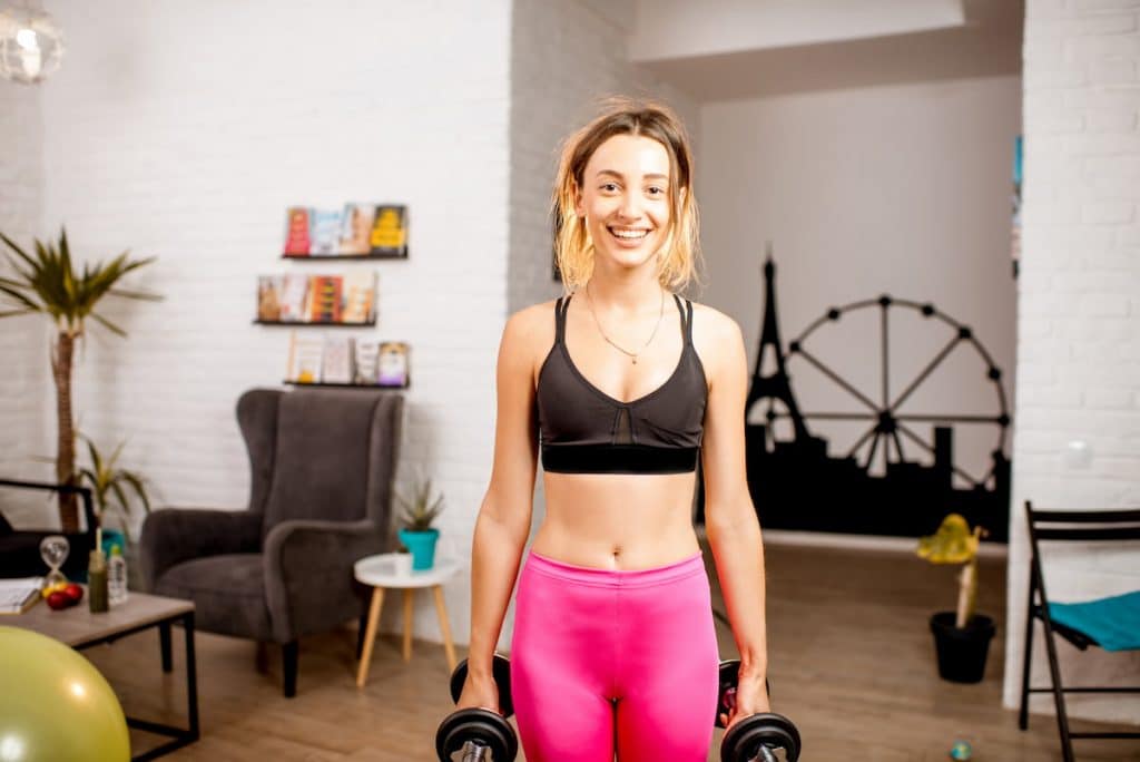 Woman doing some sports at home feeling relief after pain management treatment.