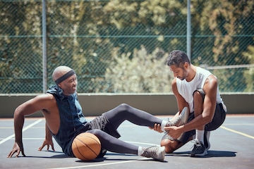 Man giving his friend a massage on the foot after getting injured from playing basketball