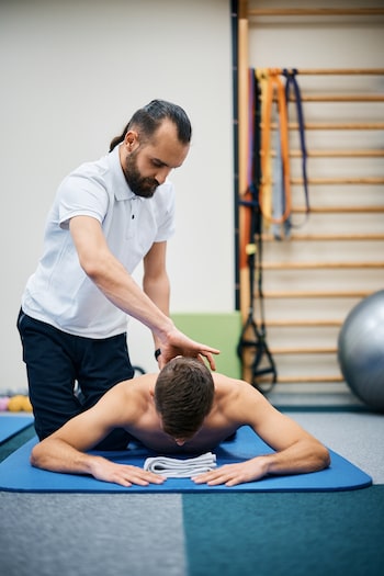 Physiotherapist massaging the neck of a man during rehabilitation service