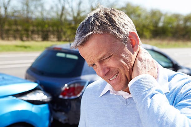 business man holding his neck from the outside of his car