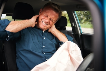 business man holding his neck while inside his car | Physical Therapy & Chiropractic