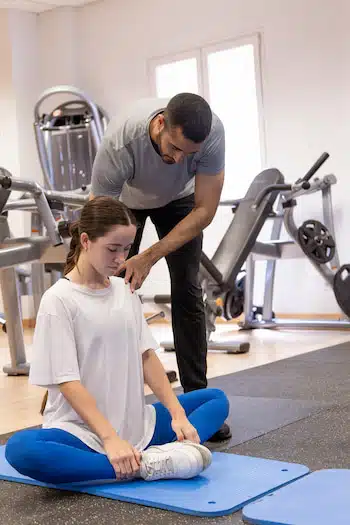 trainer corrects womans posture during gym training