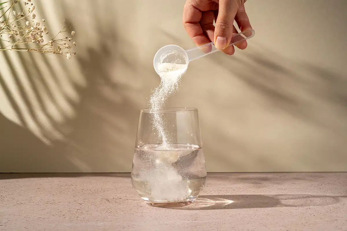 Collagen protein powder scoop and a glass of water. Food beauty and health supplement