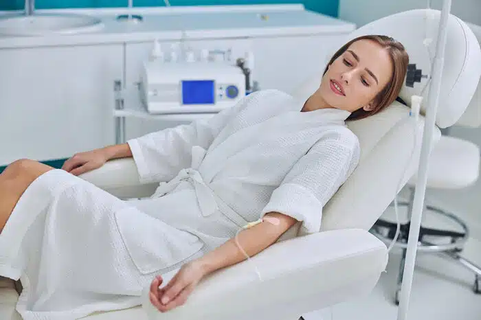 Redheaded female resting and getting her IV therapy