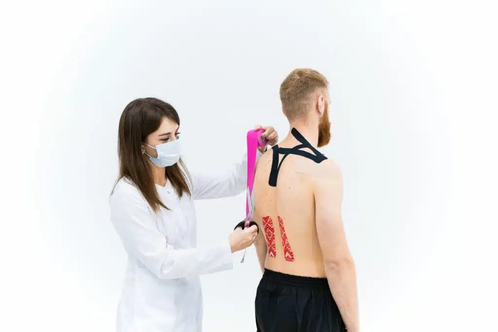 Physical therapist applying kinesiology tape to support spinal alignment in scoliosis treatment