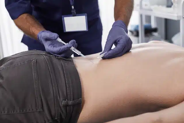 A pain management specialist performing a precise spinal injection to treat sciatica and nerve inflammation in the lower back.